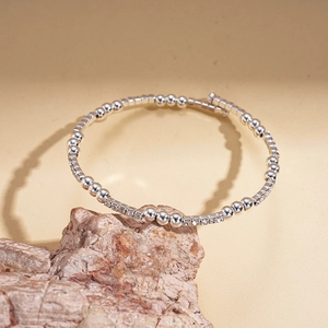Close-up of silver beaded bracelet with inlaid diamonds resting on a textured rock base