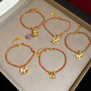 Détail de cinq bracelets en cordon rouge plaqué or 24K avec breloques de chance