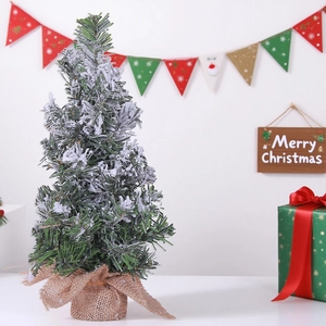 Miniature flocked Christmas tree with burlap base and festive holiday decor on white table