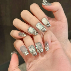 Short silver cat-eye press-on nails with green bamboo patterns and crystal rhinestones