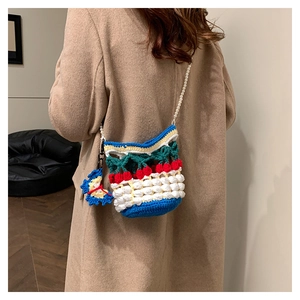Detail of hand-crocheted bucket bag with 3D cherry pattern and pearl strap on model