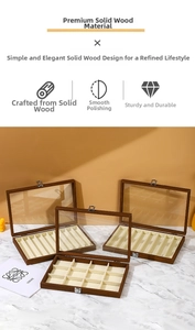 Three walnut wood jewelry boxes with glass lids and beige velvet interior on marble surface