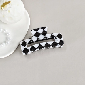 Detail of checkered cellulose acetate hair claw clip with pearl accessories