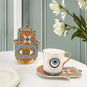 Macro shot of ceramic coffee cup with evil eye motif and Hamsa hand decorative saucer