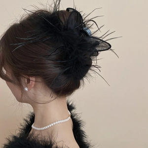 Detail of elegant black feather and mesh bunny ear hair claw clip on model's hairstyle