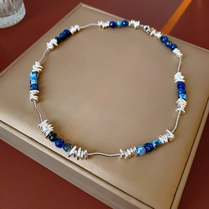 Detail of geometric blue stone beads and irregular silver metal accents on a necklace