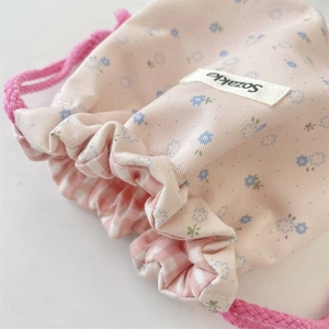 Detail of floral drawstring pouch showing pink fabric, blue flowers and grid lining
