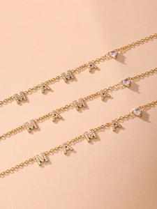 Gros plan de trois colliers MAMA en acier inoxydable plaqué or 18 carats avec cœurs CZ