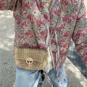 Crossbody woven straw bag with gold chain strap and round metal buckle on beige finish