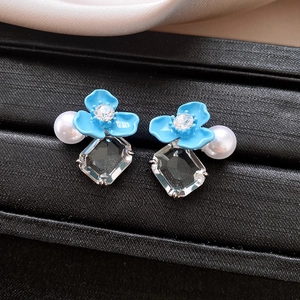 Gros plan de boucles d'oreilles fleur bleue avec perles et cristaux sur fond noir