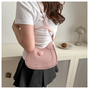 Pink heart shoulder bag shown in a cozy indoor setting with modern decor details