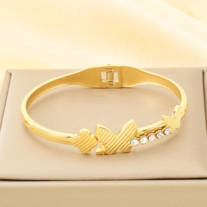 Detailed view of butterfly and clover bracelet in gold with cubic zirconia stones