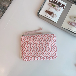 Close-up of small cotton coin pouch featuring red bow patterns and simple wish fabric label