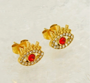 Detail of gold evil eye earrings featuring a red central stone and zircon micro-pave