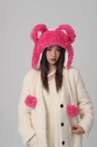 Detail of bright pink plush trapper hat featuring cute bear ears and fuzzy pompom ties