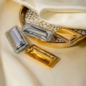 Detail of 18k gold and silver rectangular earrings with pavé stones on silk background