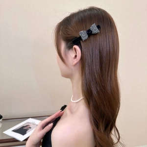 Close-up of a model wearing a black velvet bow hair clip with sparkling rhinestones