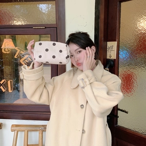Detailed texture of cream corduroy makeup bag with brown polka dots and zipper