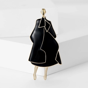 Close-up of golden enamel brooch featuring a stylish lady in a black coat silhouette
