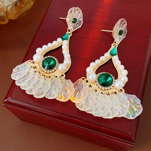 Dettaglio di orecchini vintage dorati con gemme verdi, perle bianche e petali arcobaleno