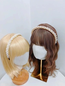 Detail of woven white pearl headband and gold double-row pearl hair accessory on models