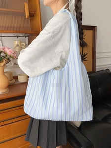 Light blue striped canvas tote bag with textured fabric shown in a home setting