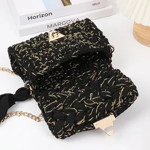 Handmade black and gold crochet crossbody bag with metal chain strap on a desk