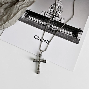 Detailed view of silver cross pendant with twisted texture on a heavy link chain necklace