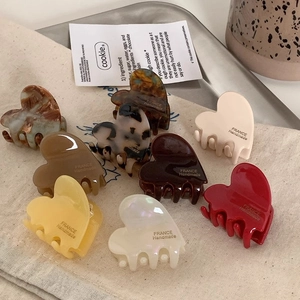 Macro shot of assorted heart-shaped acetate hair claws on a fabric and metal tray