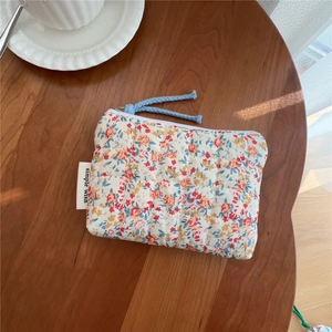 Detail of floral quilted cotton coin purse with blue zipper pull on a wooden table