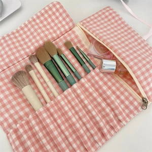 Detail of pink gingham roll-up makeup brush bag with multiple slots and zipper pocket