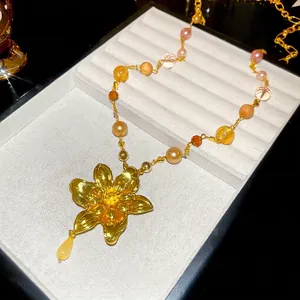 Collier vintage avec pendentif fleur, perles et ambre sur plateau à bijoux de luxe