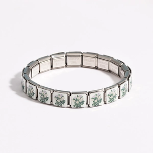 Detail of stainless steel modular charm bracelet with green and white floral enamel pattern