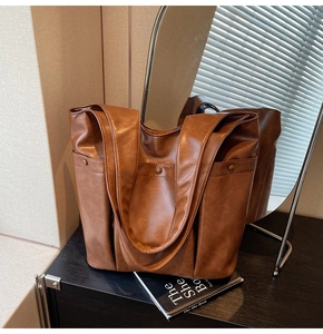 Close-up of a premium brown soft leather tote bag on a black desk with a mirror background
