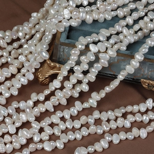 Strands of white baroque freshwater pearls draped over a vintage velvet jewelry box