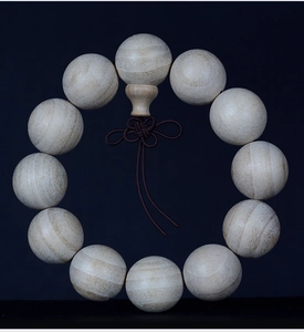 Macro detail of natural camphor wood beads with visible grain and handcrafted red knot