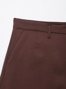 Close-up of deep brown woven blazer trousers showing waistband and side pocket detail