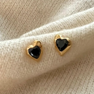 925 silver heart stud earrings with black stones on a soft white knit background