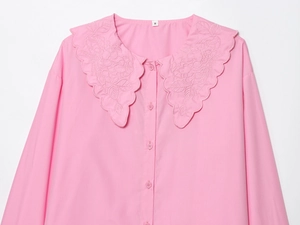 Detail of pink embroidered shirt showing intricate floral collar patterns and buttons