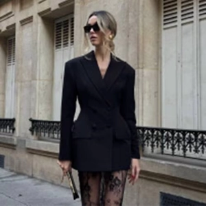 Detail of a slim-fit black waist-cinching blazer with lapels and lace accents in street style