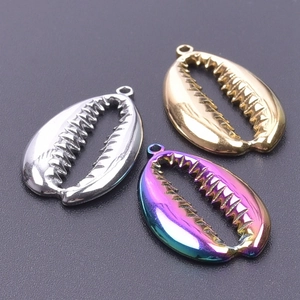 Macro shot of seashell pendants in gold, silver and rainbow finish with gear edges