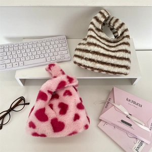 Gros plan d'un sac à main doux en peluche à motif cœur avec poignée ronde pour l'automne hiver