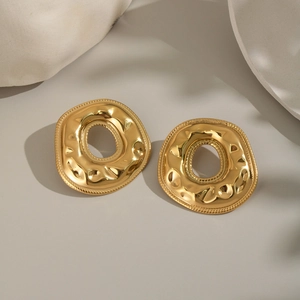 Detail of gold irregular donut earrings with textured surface and metallic luster
