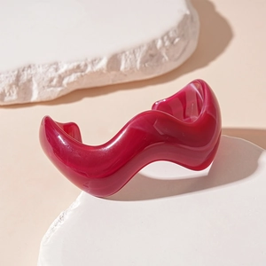 Macro detail of wave-shaped acrylic cuff bracelet with marble texture on stone display