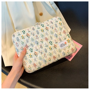 Detail of quilted floral laptop sleeve featuring colorful patterns and brand label