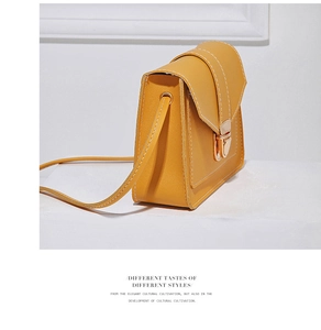 Detail of yellow minimalist crossbody bag with white stitching and golden metal lock