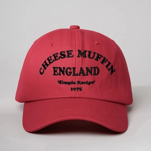 Close-up of black Cheese Muffin 1975 embroidery on a red cotton baseball cap