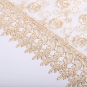 Close-up view of elegant gold lace fabric embroidery detail, intricate floral hollow pattern.