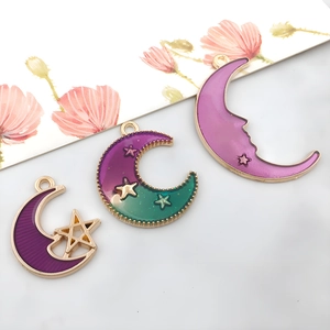 Macro view of purple enamel moon charms with gold stars for DIY jewelry crafts