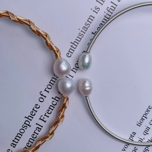 Macro shot of gold and silver wire-wrapped open bracelets with round white pearls